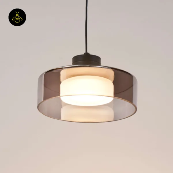 Smoked glass drum pendant light lit warm white, front view against a beige wall