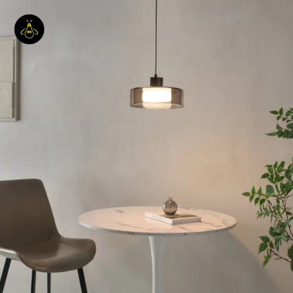 Smoked glass drum pendant light over a marble dining table in a room with wall art