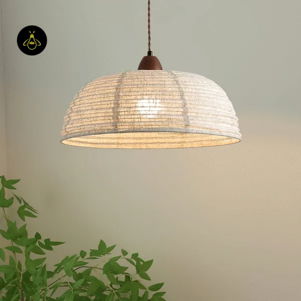 Japanese pendant lamp lit above a green plant, warm glow through the 40 cm raw silk dome