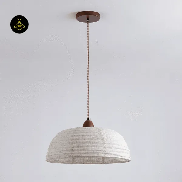 Beige raw silk dome with ribbed rings and a walnut cap hanging from a round brown stainless steel canopy on a twisted cord, Japanese pendant lamp unlit