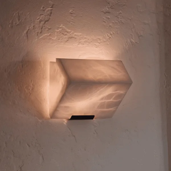 Alabaster stone wall light glowing warm on a textured plaster wall, light washing up the wall