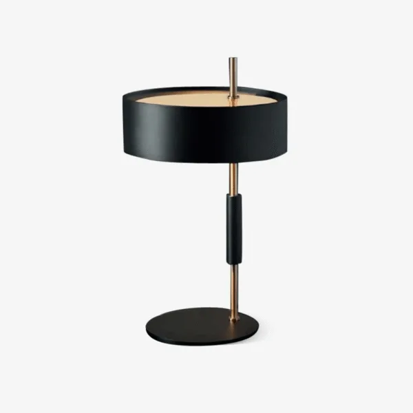 Black gold table lamp with drum shade and brass stem on a round metal base
