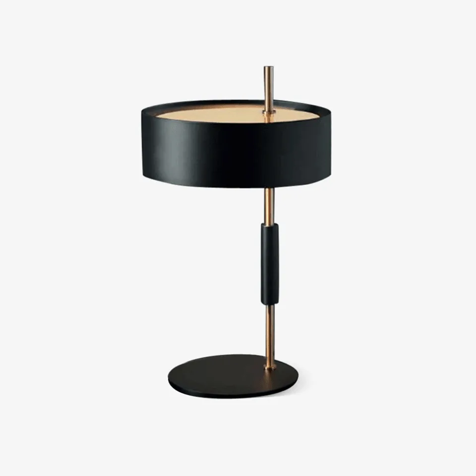 Black gold table lamp with drum shade and brass stem on a round metal base
