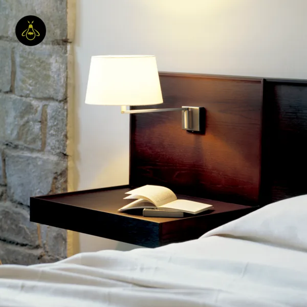 Swing arm wall lamp on a dark wood headboard, lighting an open book on the bedside shelf
