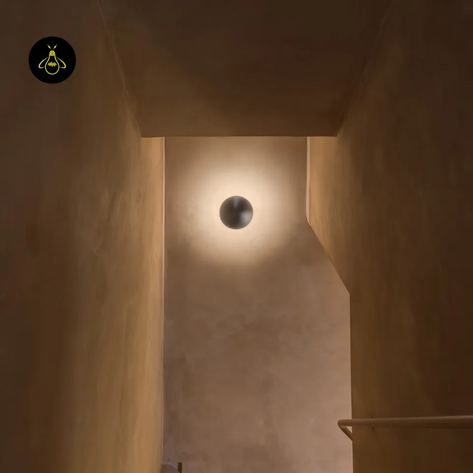 Round LED Wall Light – Satin Nickel Eclipse Disc, 24 cm Warm White Halo 6 LED wall light on the end wall of a narrow stairwell, soft warm halo on plaster