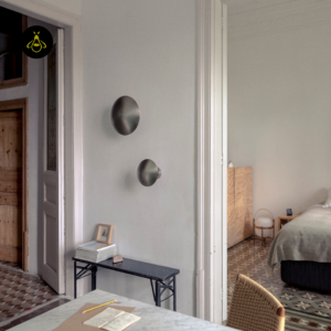 Round LED wall light in a hotel lobby, minimalist satin nickel disc