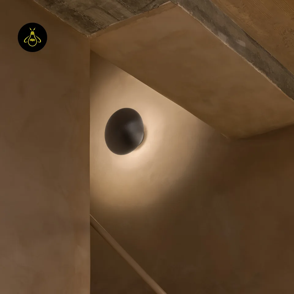 Round LED Wall Light – Satin Nickel Eclipse Disc, 24 cm Warm White Halo 10 LED wall light on a stairwell wall under a concrete ceiling, warm halo on plaster