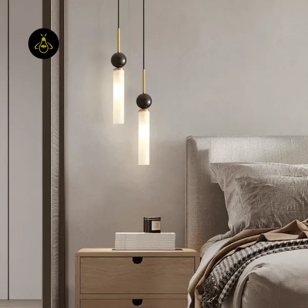 Two marble pendant light drops at different heights beside a bed, above a wooden nightstand