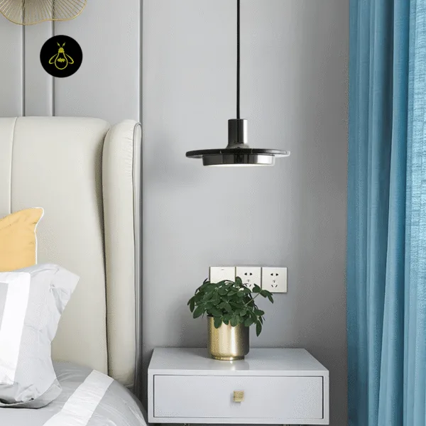 Black marble pendant light used as a bedside drop next to a cream upholstered bed