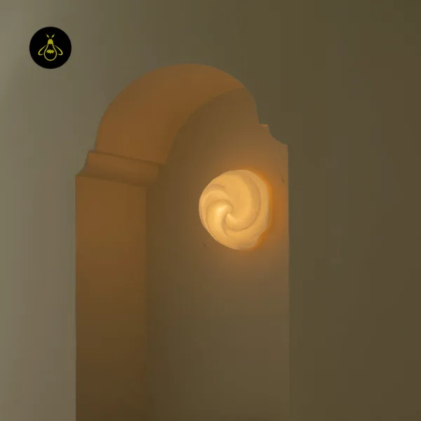 Sculptural wall light glowing inside an arched wall niche, alabaster swirl lit warm