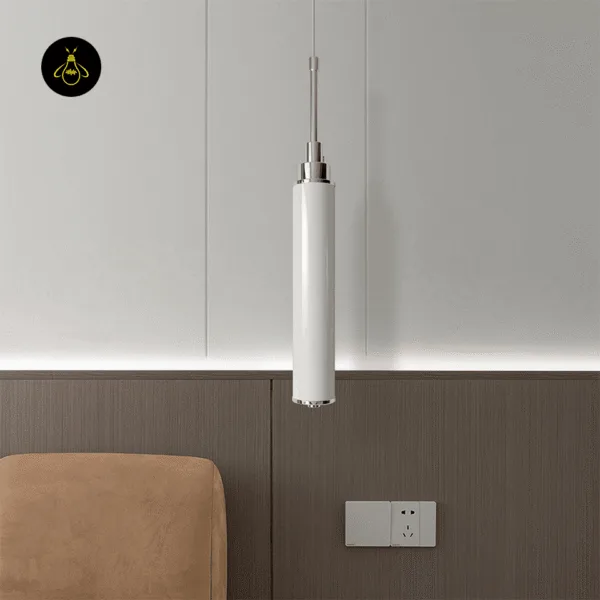 Unlit chrome cylinder pendant light hanging beside a bed, against wood and white wall panels