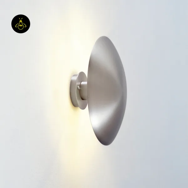 Side view of the LED wall light on a white wall, warm light washing out from behind the disc
