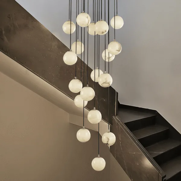 Alabaster ball chandelier cascading down a double-height staircase with a warm glow