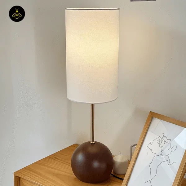 Walnut wooden sphere table lamp on a study desk giving warm task-side light
