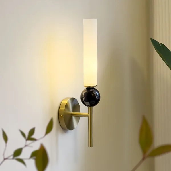 Marble wall sconce side view, white veins in the black marble sphere and warm glow on the wall
