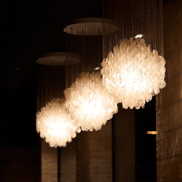 Capiz shell chandelier glowing with warm Edison-style bulbs