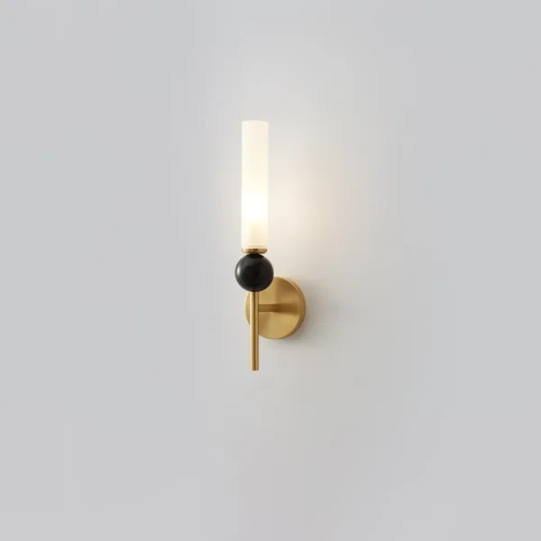 Marble wall sconce lit on a grey wall, black marble sphere below the glowing opal glass column
