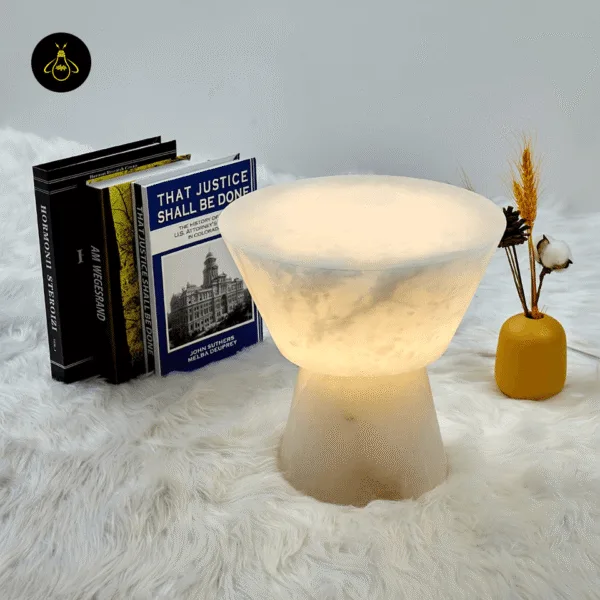 Alabaster mushroom table lamp glowing warm beside books and a yellow vase