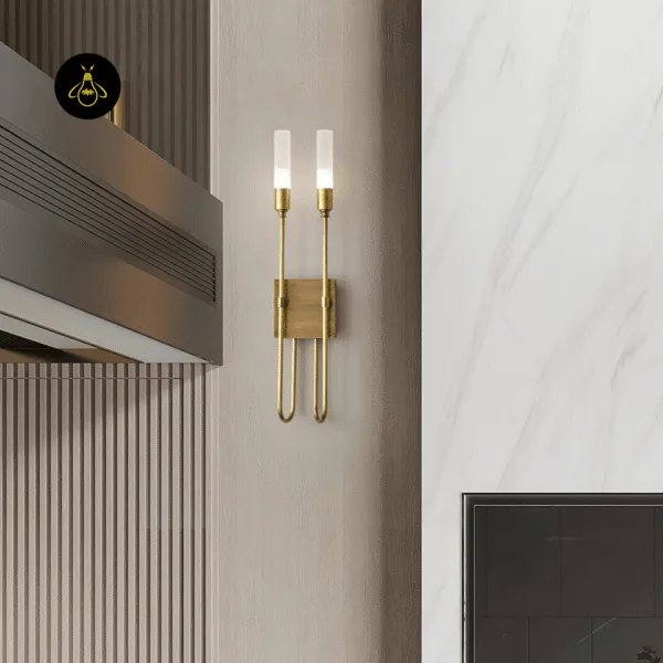 Gold wall sconce on a beige wall between a fluted wood panel and a white marble wall