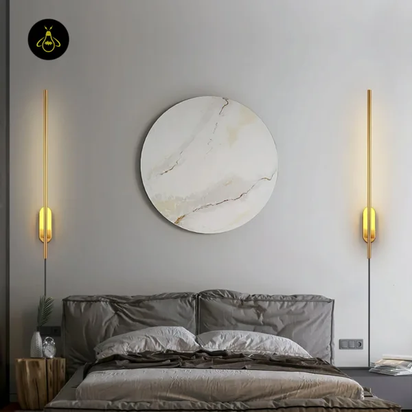A pair of brass wall sconces either side of a bed, framing round marble-pattern wall art
