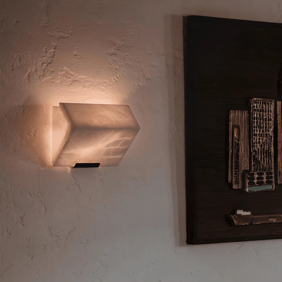 Alabaster Wall Lamp – Sculptural 15 cm Natural-Stone LED Sconce 5 Alabaster stone wall light glowing on a textured wall beside dark framed wall art in a living room