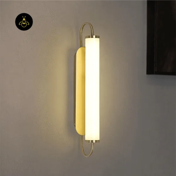 Thin wall light lit at an angle, showing the gold oval backplate and looped rod beside a dark wooden frame