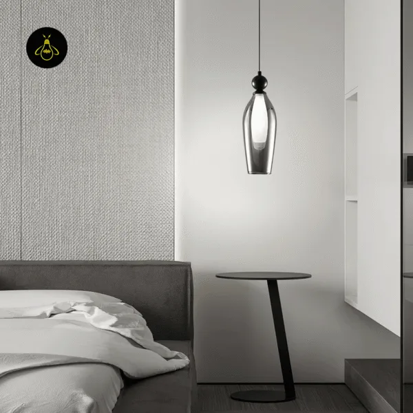Slim black smoked glass pendant light over a bedside table in a modern bedroom