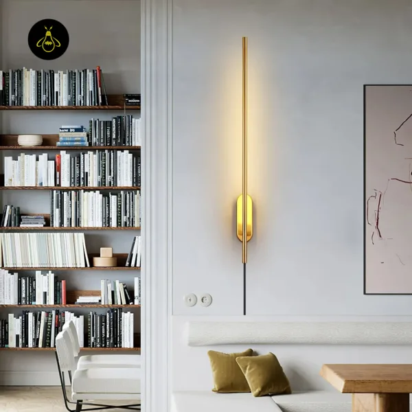 Brass wall sconce lit above a cream sofa bench in a living room beside bookshelves