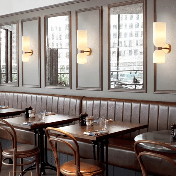 Opal glass wall sconce for bedroom or dining space, shown in a row lighting a banquette between mirror panels
