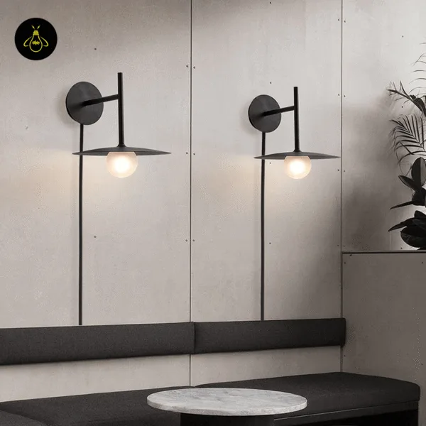 Two black wall lamps on a panelled wall above a lounge bench