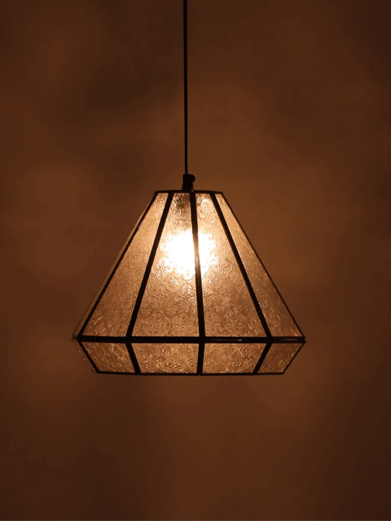 Moroccan pendant light glowing warm through textured arabesque glass panels in a gold lantern frame