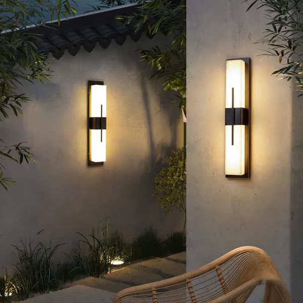 Pair of alabaster outdoor wall lights glowing on patio walls above a garden path
