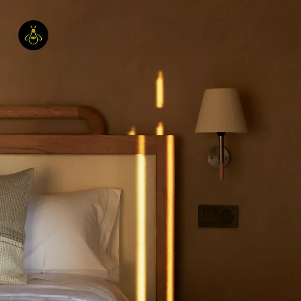 Fabric wall light beside a wooden headboard, warm evening light in a bedroom
