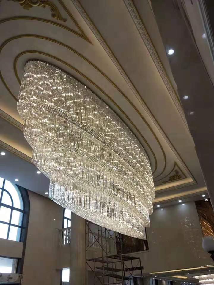 Crystal lobby chandelier glowing beneath a gold-trimmed recessed ceiling in Jaipur