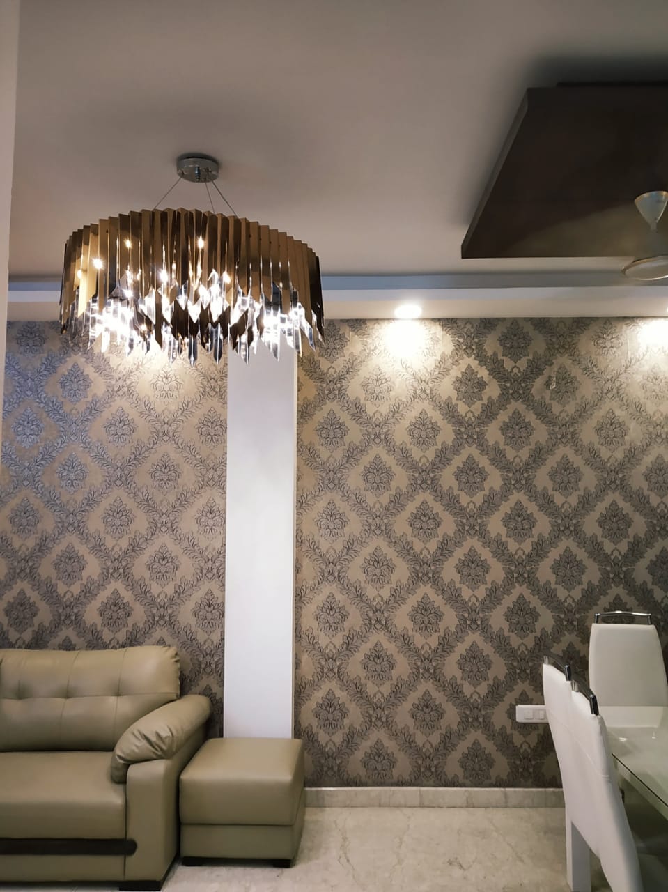 Decorative residential chandelier glowing warmly above the living and dining space in Delhi