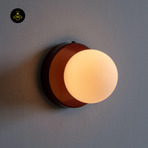 Round red wall light with white glass globe glowing warm for a bedroom