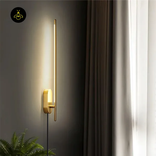 Brass wall sconce beside long curtains, angled view of the slim rod, backplate and black cord