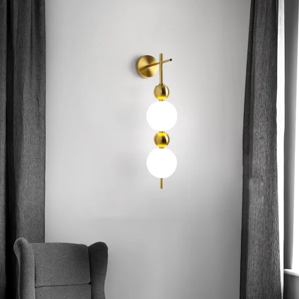 Bedside wall light lit on a pale wall between grey curtains above a grey armchair