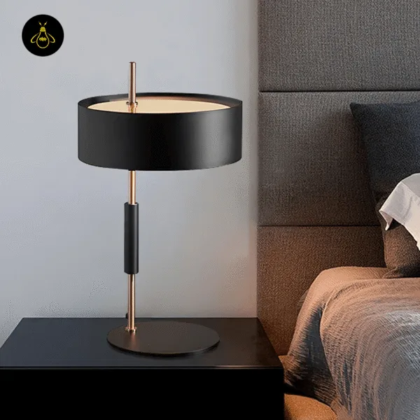Black gold table lamp with drum shade on a bedroom nightstand