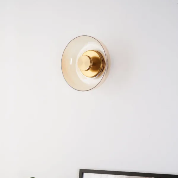 Circular wall light switched off on a white wall above a picture frame