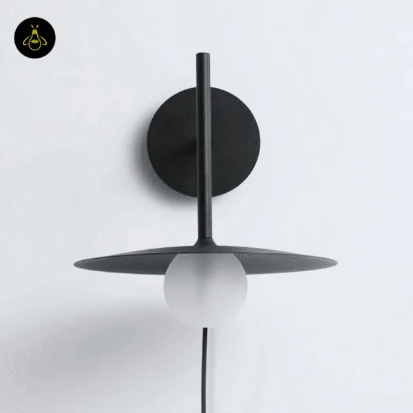 Black wall lamp on a white and grey textured wall, frosted globe under the round disc