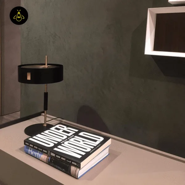 Black gold metal table lamp casting a soft downward glow over books