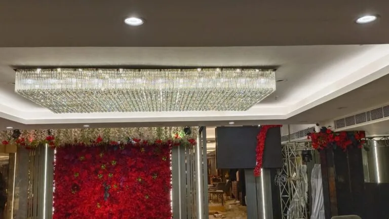 Banquet chandelier Ghaziabad — rectangular crystal ceiling chandelier glowing above the wedding stage at Tunight Restro and Banquet, Raj Nagar