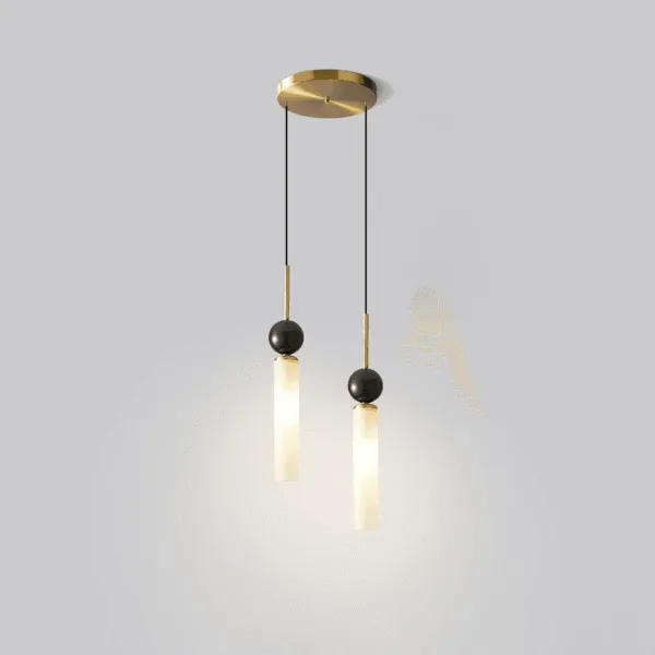 Double marble pendant light lit, white marble cylinders glowing warm under black marble spheres