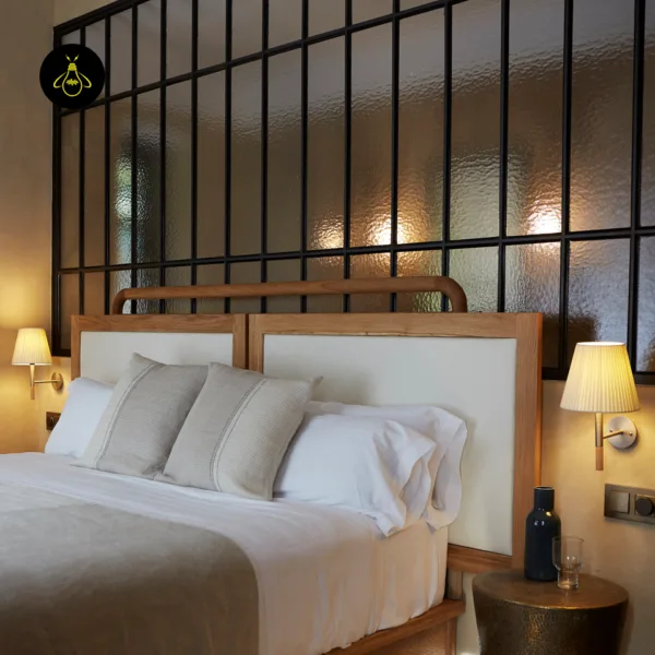 Pair of fabric wall lights flanking a double bed under a glass partition wall