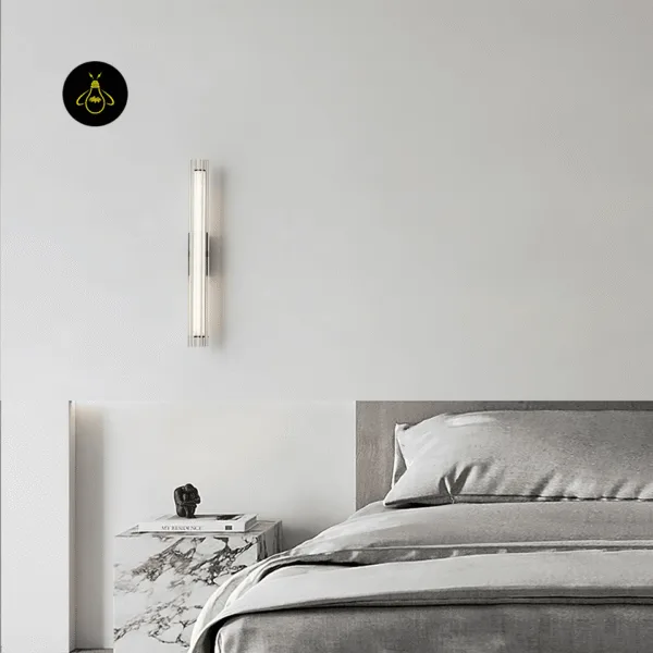 Fluted glass bedside wall lamp above a marble nightstand beside a grey upholstered bed