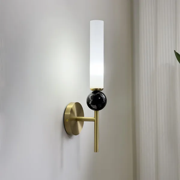 Marble wall sconce on a white wall beside sheer curtains, side view of the arm and marble sphere
