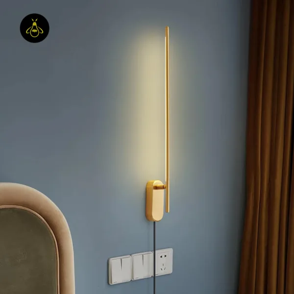 Brass wall sconce glowing on a blue bedroom wall beside an upholstered headboard