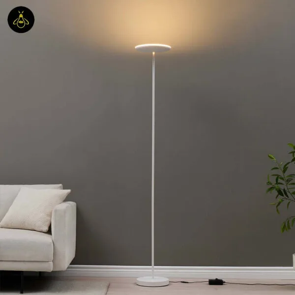 Matte white LED floor lamp with adjustable head casting warm uplight beside a sofa in a living room