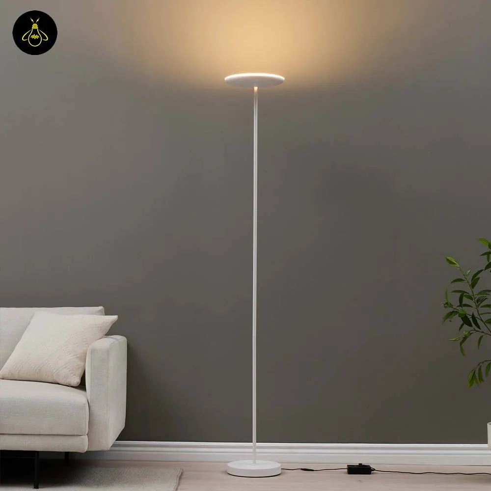 Matte white LED floor lamp with adjustable head casting warm uplight beside a sofa in a living room